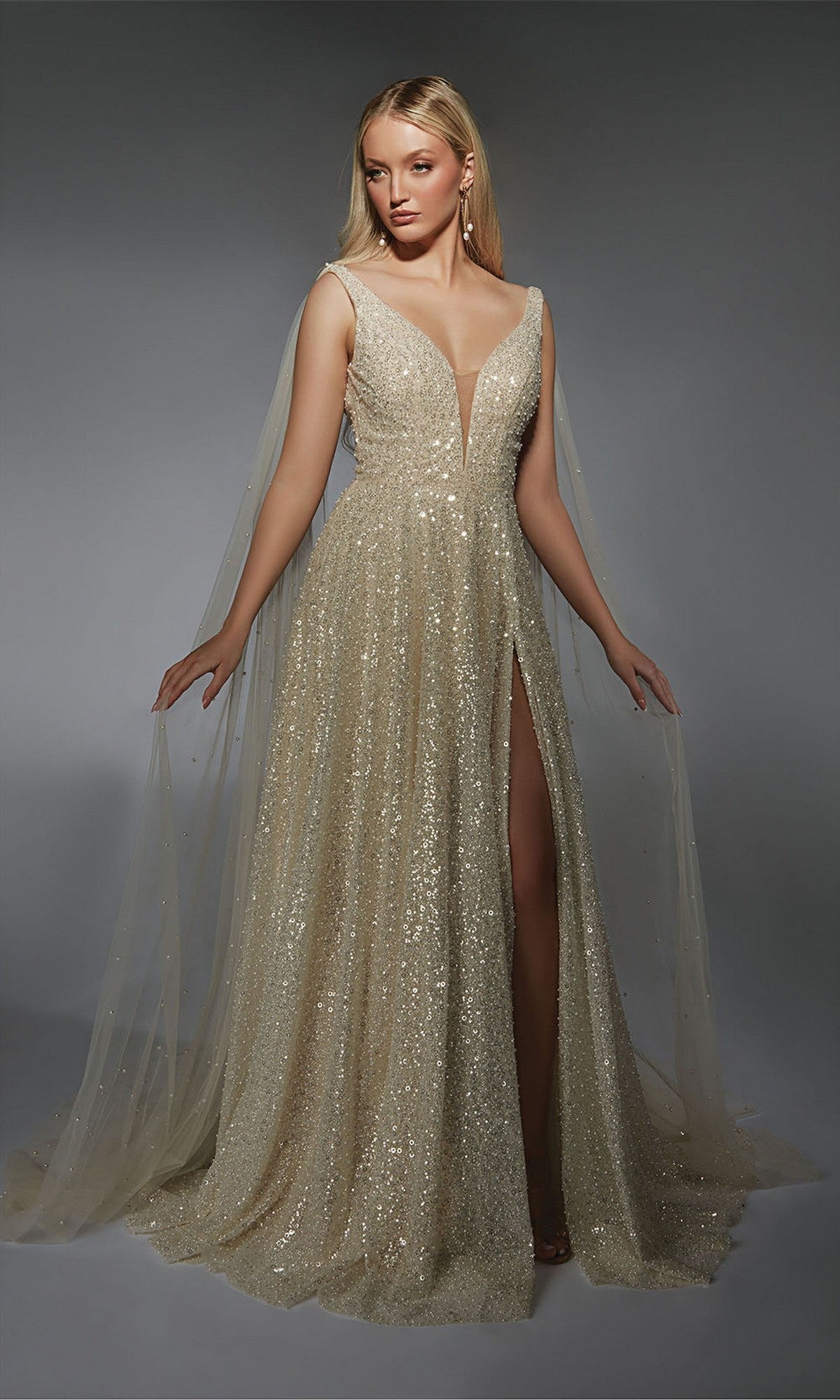 A woman wearing the Alyce 7134 long white dress in light champagne, a sleeveless, floor-length evening gown with sequins, deep V-neckline, thigh-high slit, and sheer tulle shoulder panels.
